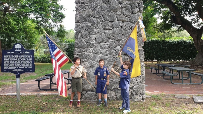Scout and Cubs with flags in front of chimney